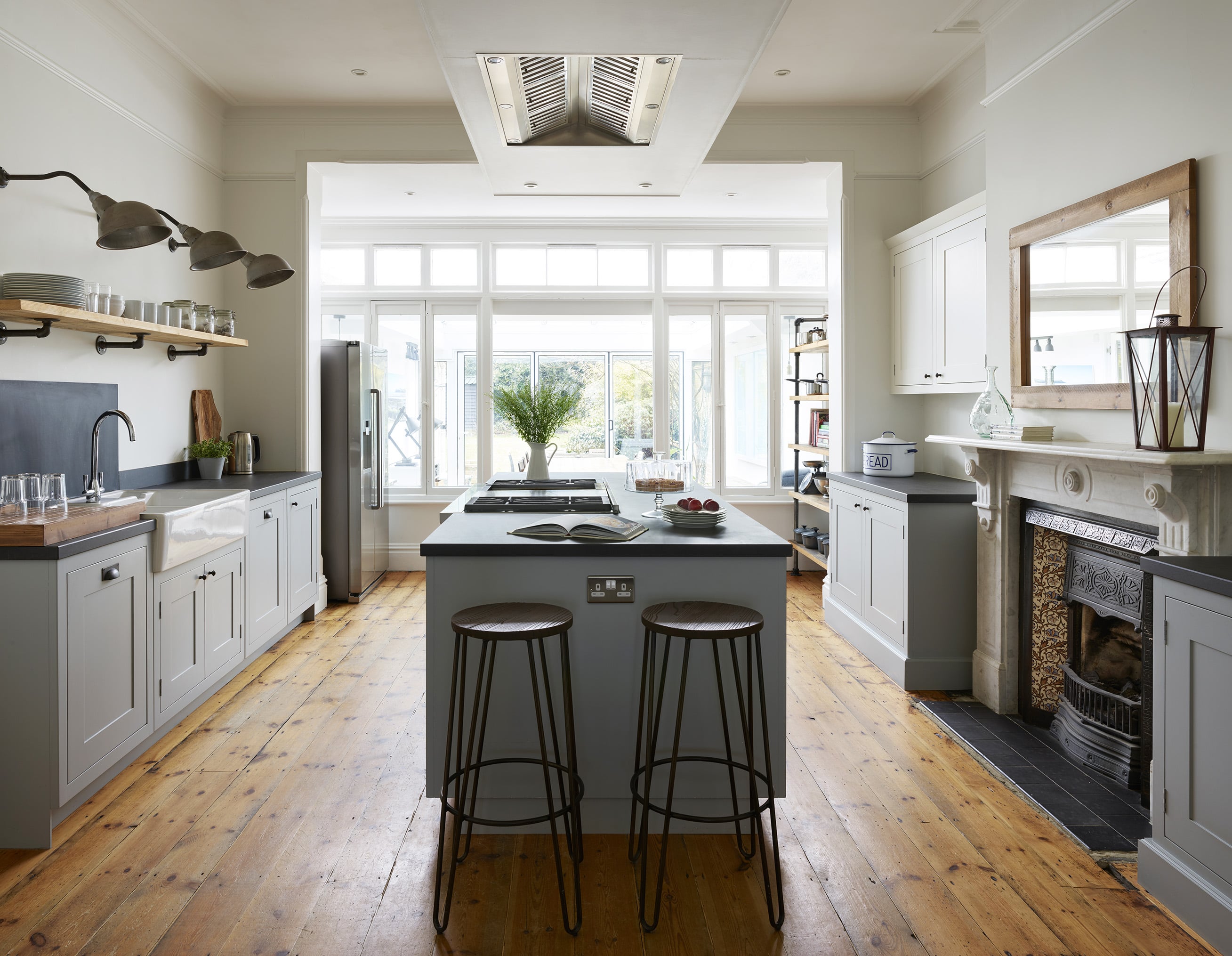 kitchen with hardwood floors, island with stools, large windows, and wooden shelves