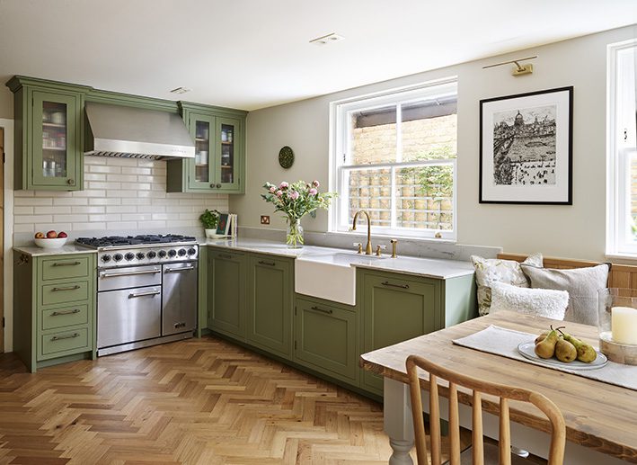 green kitchen cabinetry and gold accessories